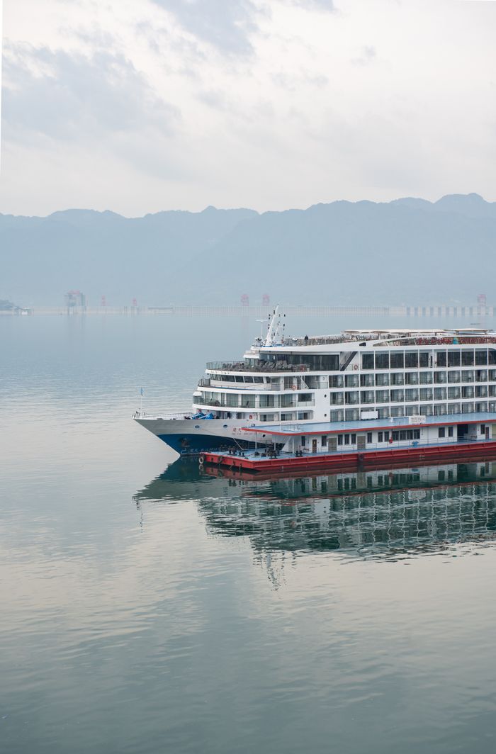 about-us-01 Luxury cruise ship navigating serene waters with mountain backdrop.